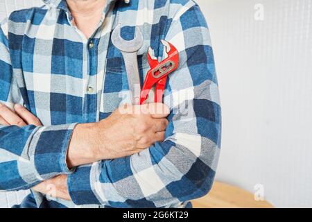 Installatore o idraulico con chiave per tubi e chiave fissa come simbolo di competenza Foto Stock