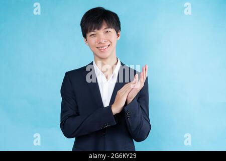 Immagine di un giovane uomo d'affari asiatico che indossa un vestito su sfondo blu Foto Stock