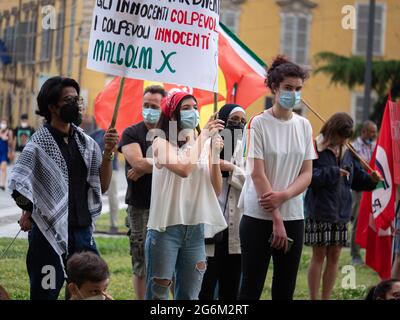 Ragazze con veli sulle loro teste e maschere chirurgiche sui loro volti durante un evento politico in Piazza pubblica con il segno più potente. Foto Stock