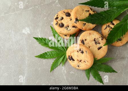 Biscotti e foglie di cannabis su tavola grigia testurizzata Foto Stock