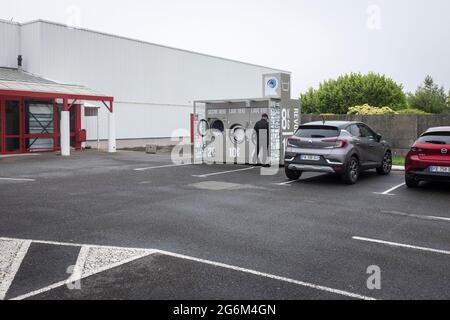 Un'ampia foto di un uomo che fa la sua lavanderia in una lavanderia all'aperto in un parcheggio supermercato a Plousgasnou, Francia Foto Stock