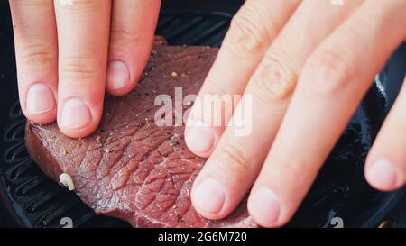 Vista dal taglio dello chef che mette una bistecca di manzo speziata sul piatto della griglia Foto Stock