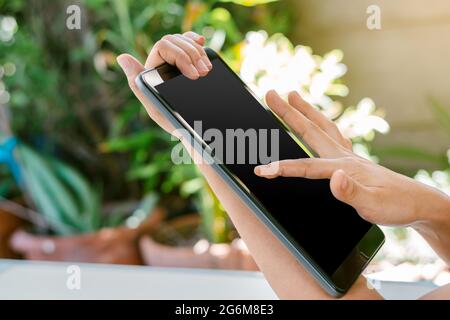 La mano della donna tocca lo schermo nero del tablet, utilizzando concetti di tecnologia e social media. Foto Stock