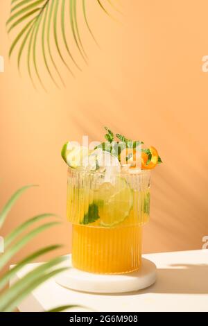 Cocktail classico di freschezza, mojito, limonata o mai tai con lime, arancio sulla moderna still life sul podio su sfondo beige con ombra. Parte festiva Foto Stock