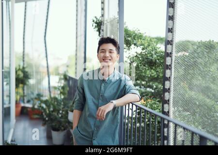 Giovane ragazzo asiatico che aspetta e si appoggia nel corrimano Foto Stock