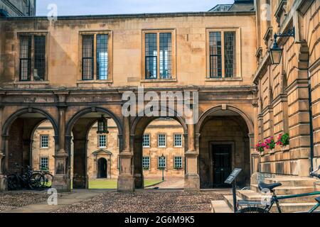 First Court of Peterhouse College University of Cambridge con passerella ad arco con gallerie sopra e cicli in primo piano su terreno acciottolato Foto Stock