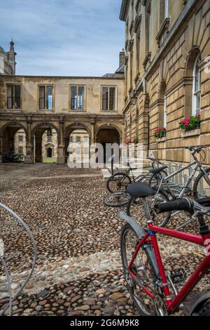 First Court of Peterhouse College University of Cambridge con passerella ad arco con gallerie sopra e cicli in primo piano su terreno acciottolato. Foto Stock