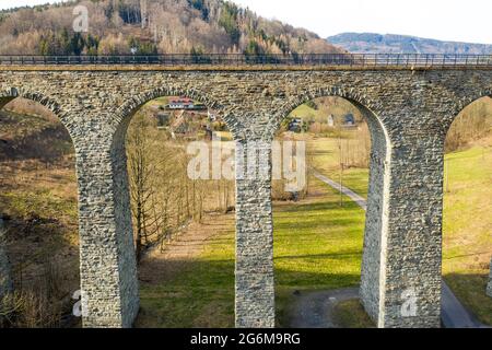 Vista aerea del ponte ad arco viadotto vicino al piccolo villaggio nella foresta. Foto Stock