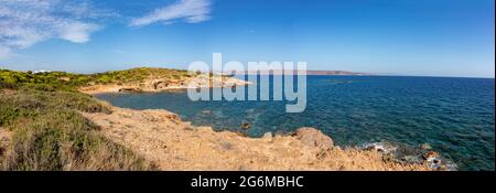 Roccioso, con cespugli verdi, scogliere selvagge, vista sulla linea costiera nei pressi di Atene, Grecia. Vivace e colorata vista estiva con blu mare Mediterraneo chiaro Foto Stock