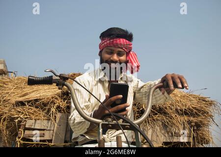 Giovane uomo che guida la macchina rickshaw e usando lo smartphone Foto Stock