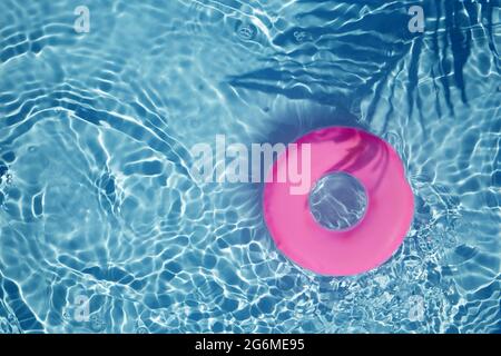 Anello di galleggiamento della piscina rosa che galleggia in una rinfrescante piscina blu. Vista dall'alto Foto Stock