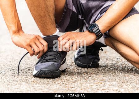 I corridori stanno legando le loro lacci, corre nel parco. Primo piano uomo legando scarpe da jogging. Foto Stock