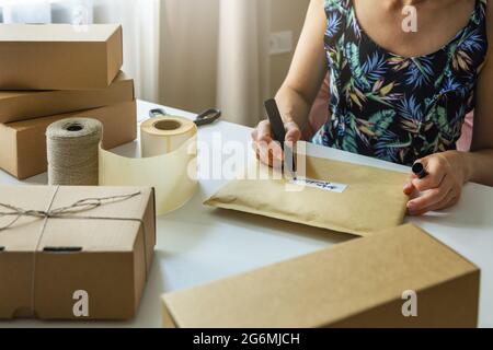 il proprietario del piccolo negozio online scrive l'etichetta di spedizione della busta a casa per la consegna della spedizione Foto Stock