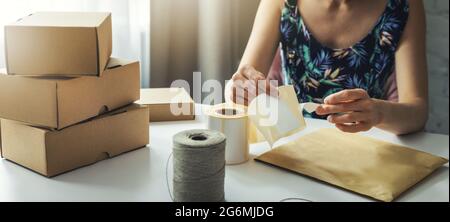 piccolo proprietario in linea di affari che prepara l'etichetta di spedizione del pacco a casa per la consegna del trasporto. banner Foto Stock