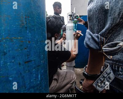 Giacarta, Indonesia. 07 luglio 2021. I parenti dei pazienti covid-19 aspettano all'esterno di un centro di rifornimento di ossigeno per riempire le loro bombole vuote, in quanto la domanda di gas aumenta a causa del picco nei casi di coronavirus. Gli aumenti dei terribili casi di Coronavirus hanno provocato carenze di ossigeno in Indonesia, segnalate dal fornitore di ossigeno martedì. Credit: SOPA Images Limited/Alamy Live News Foto Stock