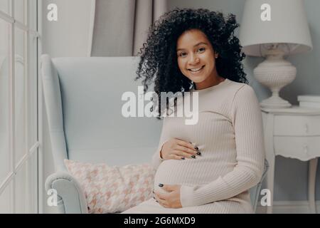 Bella donna africana incinta godendo di gravidanza, trascorrere il tempo a casa Foto Stock