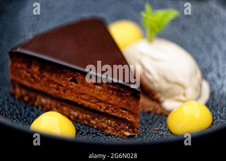 Primo piano di appetitosa torta al cioccolato fondente con gel d'arancia e gelato al carciofo Foto Stock
