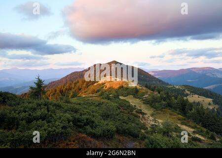 Paesaggio montano con splendidi tramonti, cielo nuvoloso e orizzonte arancione colorato. Fantastico paesaggio rurale d'autunno. Foto Stock