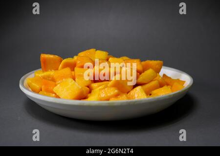 Cubetti di Mango in un piatto bianco su sfondo nero isolato Foto Stock