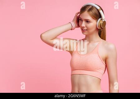 Felice donna sportiva in tuta che celebra il suo successo su isolato sfondo rosa Foto Stock