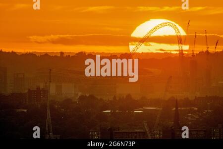 Il sole tramonta sullo stadio Wembley, perfettamente dietro l'arco Foto Stock