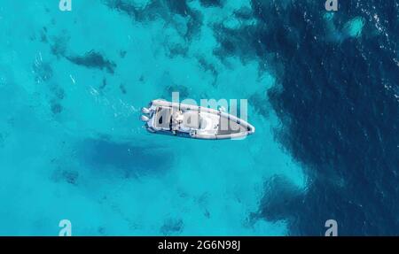 Motoscafo gommoni gommoni su fondo mare turchese di colore blu. Vista dall'alto del drone aereo. Motoscafo che naviga lentamente su acqua increspata. Mar Egeo, Foto Stock