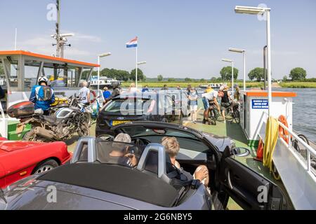 Traghetto con auto, biciclette e pedoni vicino al villaggio olandese Cuijk Foto Stock