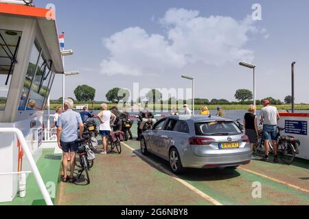 Traghetto con auto, biciclette e pedoni vicino al villaggio olandese Cuijk Foto Stock