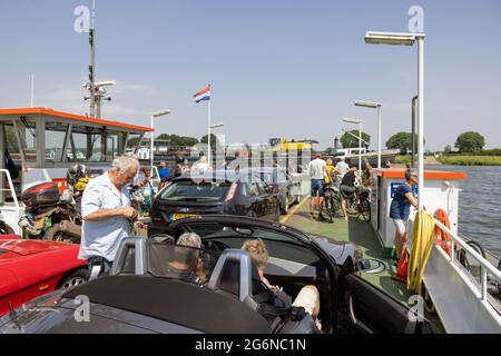 Traghetto con auto, biciclette e pedoni vicino al villaggio olandese Cuijk Foto Stock