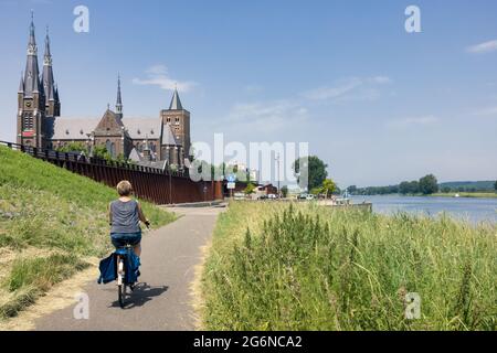 Donna in bicicletta lungo il fiume Mosa vicino al villaggio olandese Cuijk Foto Stock