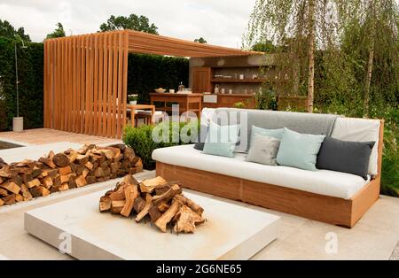 Posti a sedere, aree da pranzo e una cucina esterna circondata da confini nel Viking Friluftsiv Garden all'Hampton Court Palace Garden Festival 2021 Foto Stock