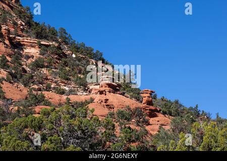 Formazioni rocciose di arenaria rossa a forma di hoodoo sul lato di una montagna e circondate da cespugli di deserto e alberi vicino al Parco Nazionale di Zion. Foto Stock