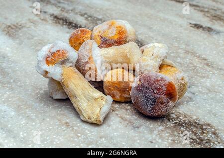 Funghi surgelati su sfondo di legno. L'intero boletus viene congelato nel congelatore. Foto Stock