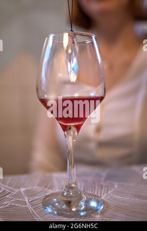 Un bicchiere di vino rosso sul tavolo con un cristallo all'interno. Foto Stock