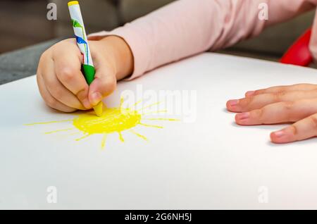 Istruzione e scuola. Concetto di educazione e asilo. Carina bambina disegna il sole con matite. Foto Stock