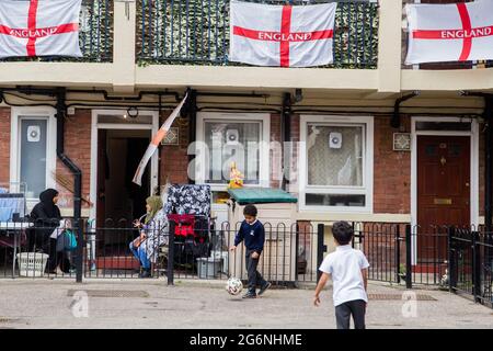 Londra, Regno Unito. 07 luglio 2021. I bambini giocano nella tenuta Kirby di Bermondsey, a sud-est di Londra. Un'abitazione è stata coperta con bandiere inglesi prima della partita semifinale contro la Danimarca. (Foto di Thabo Jaiyesimi/SOPA Images/Sipa USA) Credit: Sipa USA/Alamy Live News Foto Stock