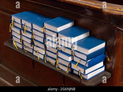 Una pila di libri per la preghiera e i religiosi cantano sullo scaffale della chiesa Foto Stock