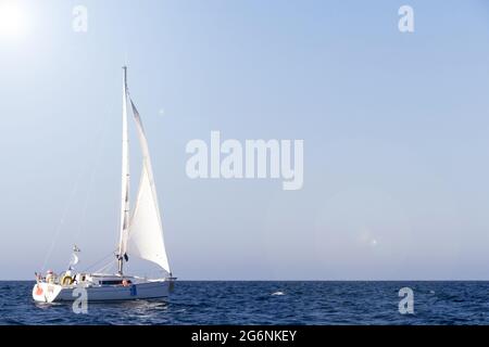 Barca a vela con vele bianche sotto il sole in Bretagna Foto Stock