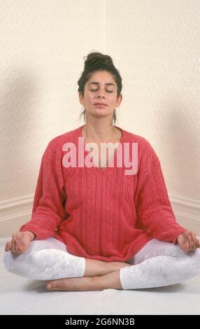 donna incinta anglo-indiana in posizione yoga loto meditando Foto Stock