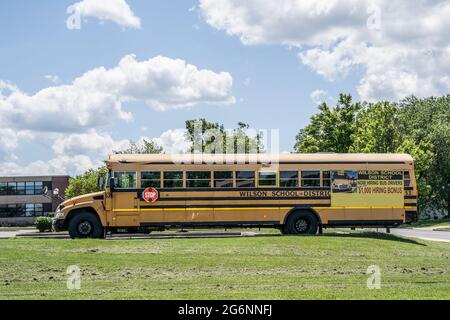 Berks County, Pennsylvania-16 giugno 2021: School Bus parcheggiato a scuola locale con segno che offre bonus di affitto per i conducenti di autobus Foto Stock