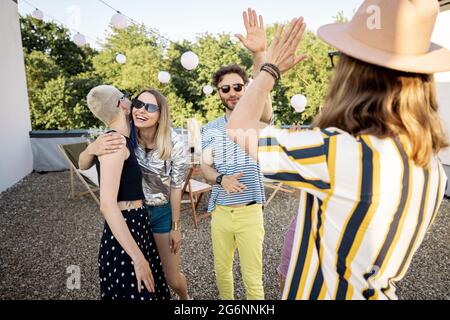 I giovani amici alla moda saluta alla festa all'aperto Foto Stock