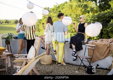 Giovani amici alla moda che hanno una cena festosa sulla terrazza sul tetto Foto Stock
