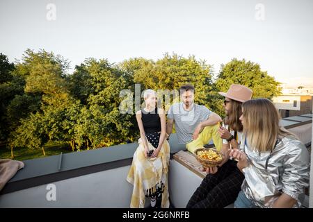 Gli amici si ritrovano sul tetto al tramonto Foto Stock