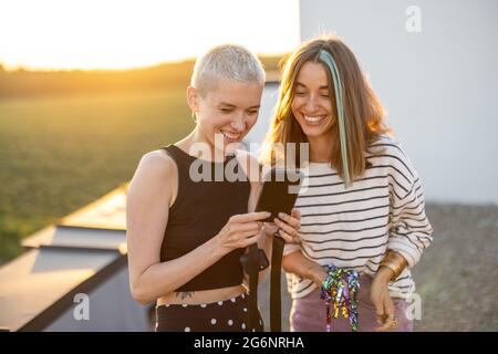 I giovani amici si divertono sulla terrazza sul tetto al tramonto Foto Stock