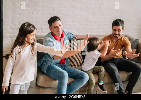 Coppia gay che gioca con i loro bambini a casa. Foto Stock