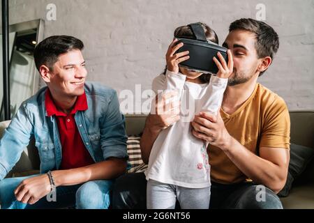 Coppia gay e i loro figli che giocano con i video giochi con occhiali VR. Foto Stock