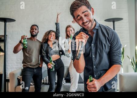 Gruppo di amici che giocano al karaoke a casa. Foto Stock