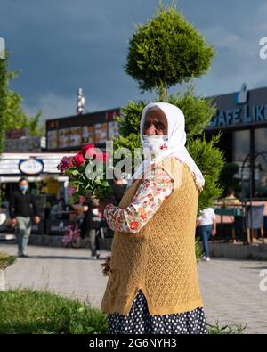 Amasra, Turchia - Giugno 26 2021: Donna che vende rose in abito locale e tradizionale Foto Stock