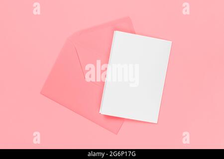 Cartoncino bianco vuoto con busta rosa isolata su sfondo blu. Template o mock-up. Banner con spazio per la copia Foto Stock