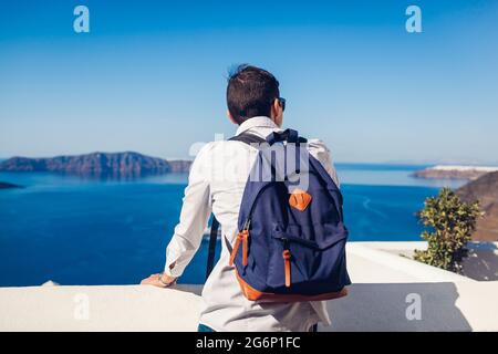 Il viaggiatore di Santorini gode della vista della Caldera da Fira o Thera, Grecia. Backpacker guardando il paesaggio del mare Egeo. Turismo, viaggi, vacanze estive Foto Stock